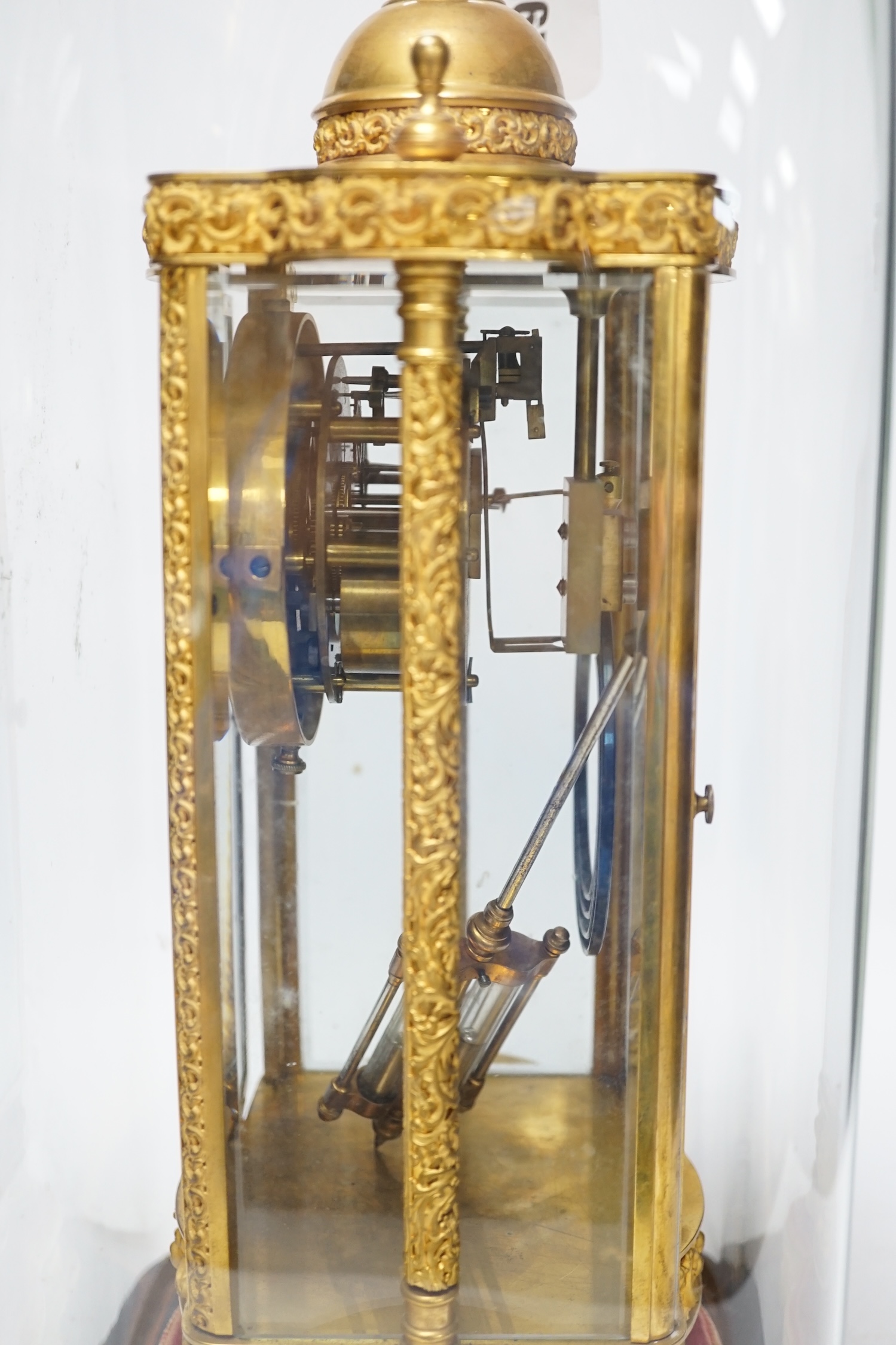 A French four glass mantel clock striking on a coiled gong with gilt brass frame and mercury pendulum, on a stand under a glass dome, 55cm high, with brass presentation label to stand dated December 1903